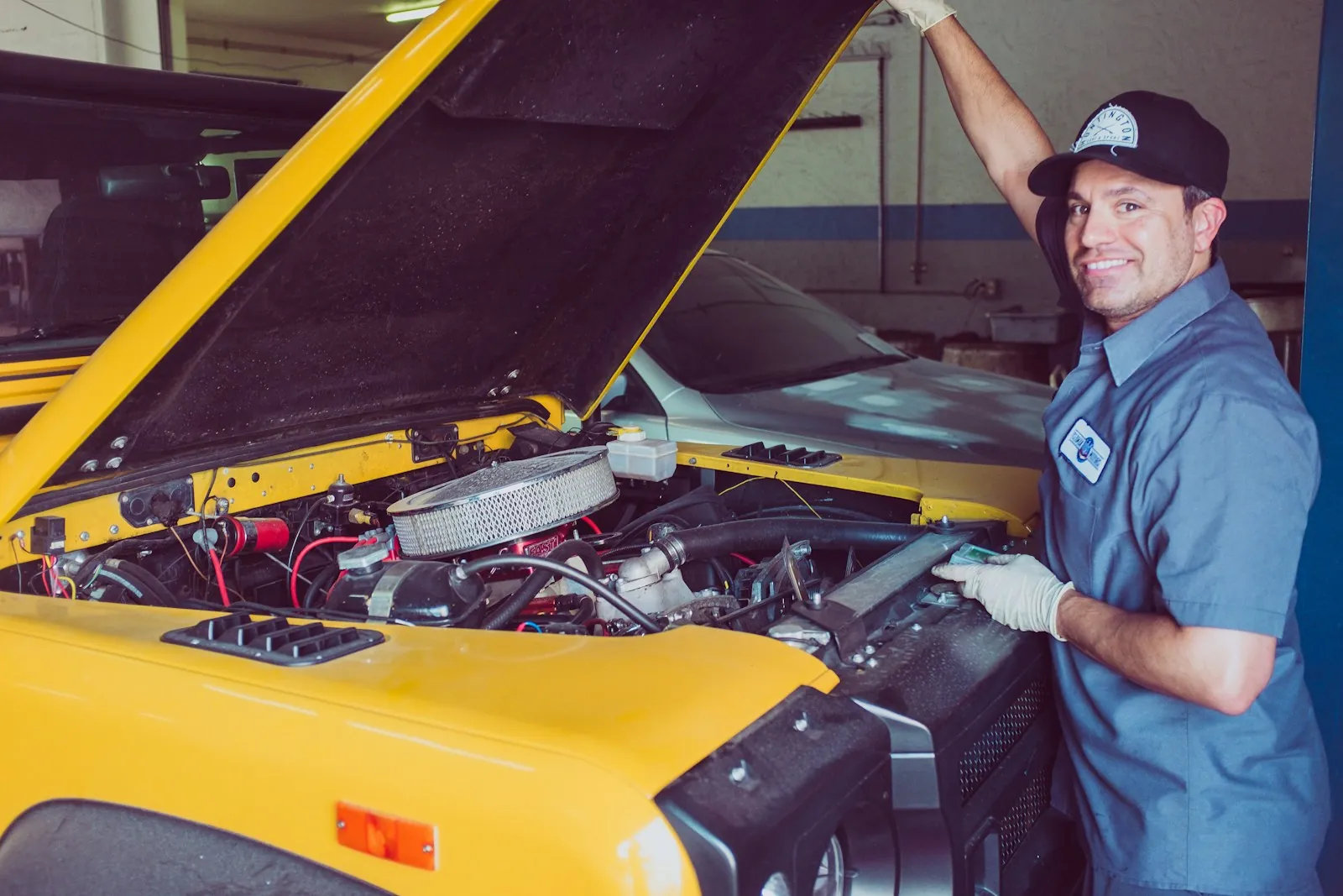 Smiling mechanic working under the bonnet of a car