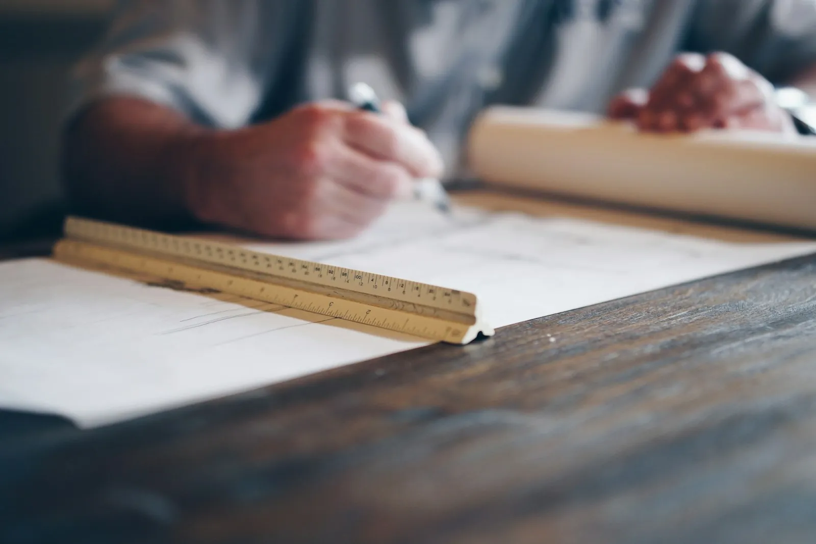 Hands drafting detailed plans with a pencil and ruler