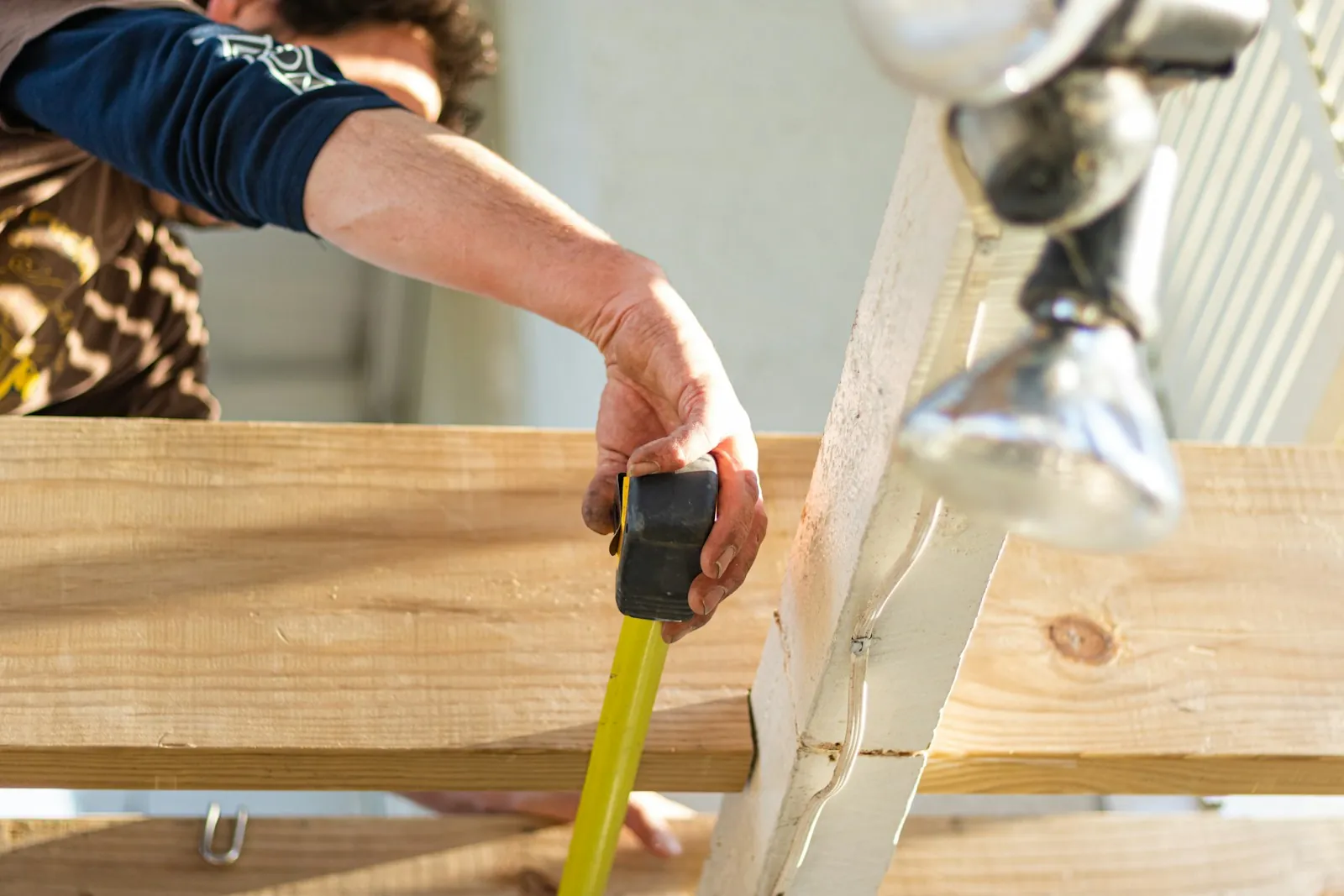 Carpenter measuring a timber board with a tape measure