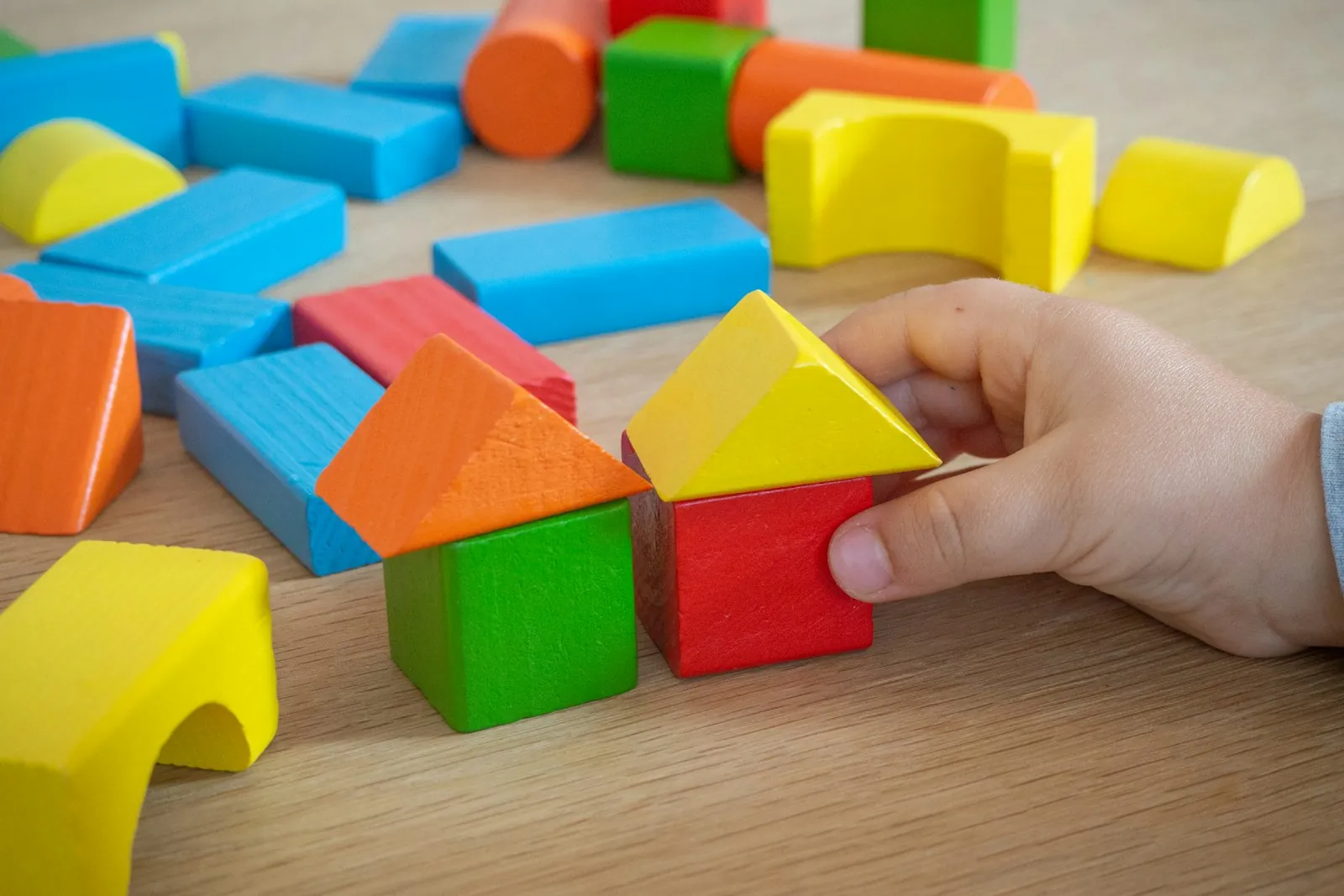 Child building a house from colourful wooden blocks