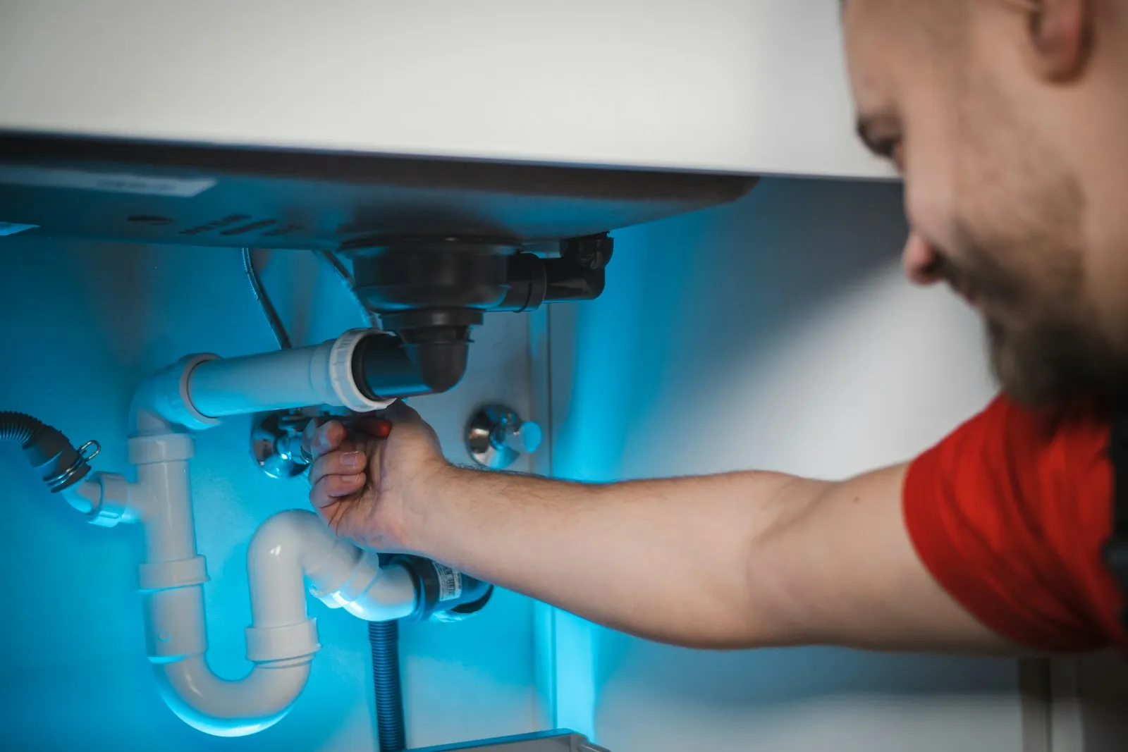 Tradesman fixing a pipe under a sink