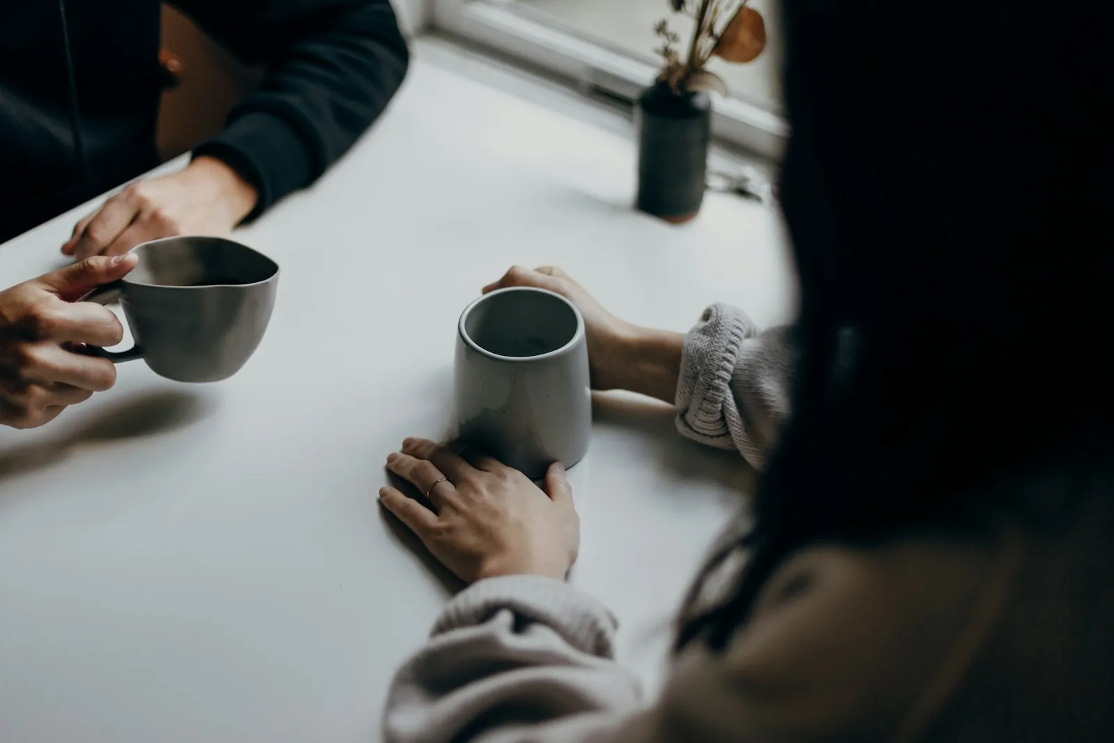 Two people chatting over mugs of coffee